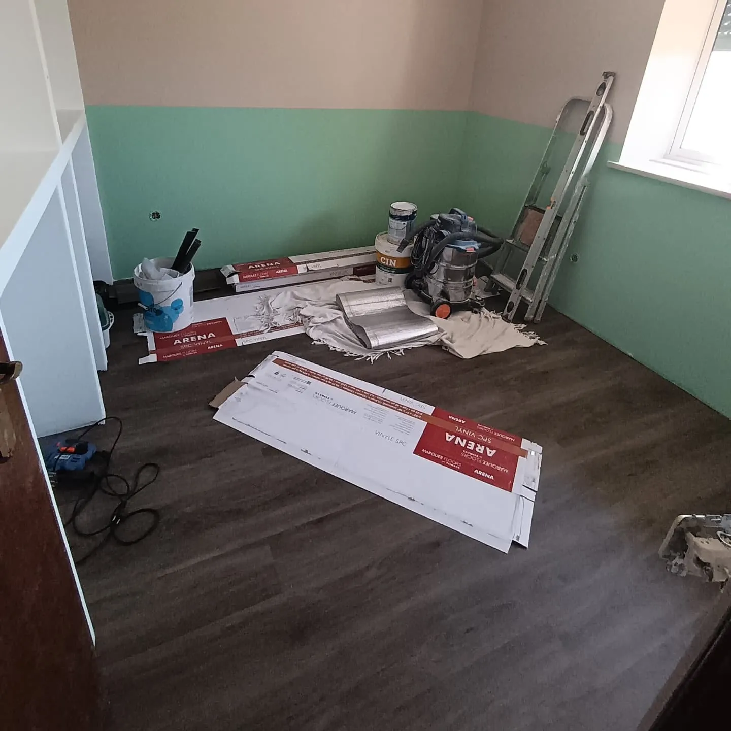 Quarto durante a remodelação, com pavimento vinílico aplicado e materiais de obra